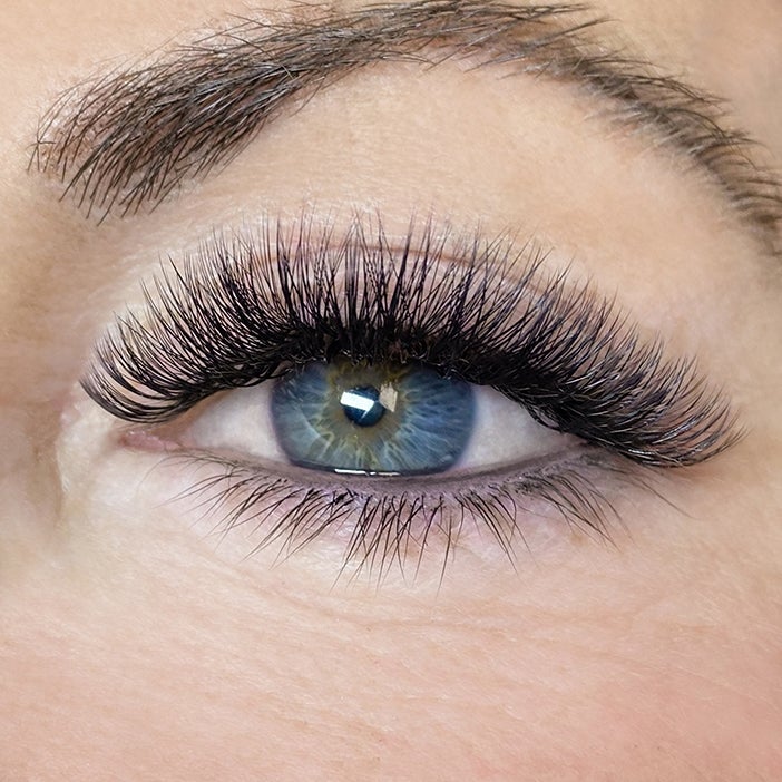 A close-up of an eye with textured russian lash extensions for a dense lash line