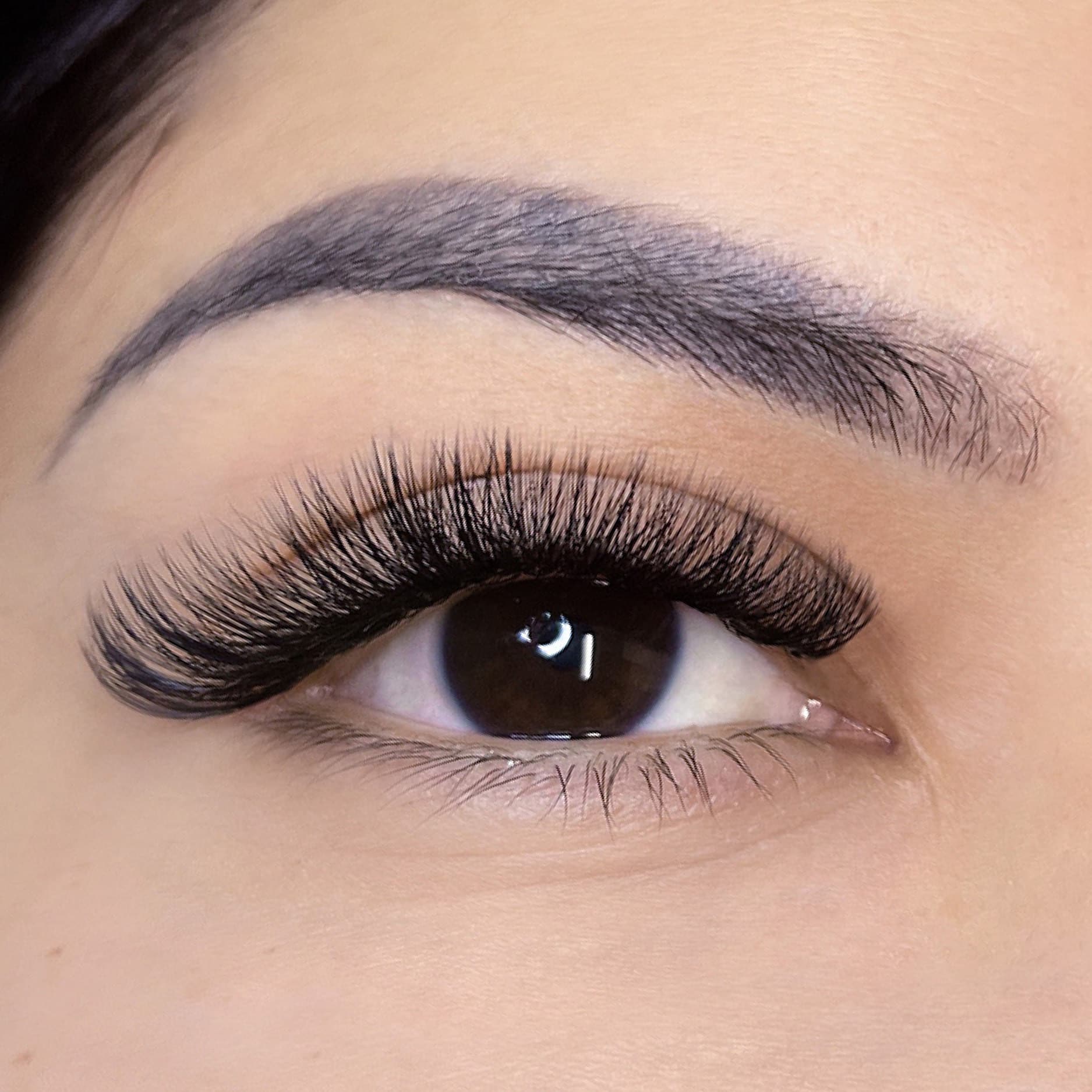 A close up of a woman's eye with lash extensions that give her eye a naturally lifted look