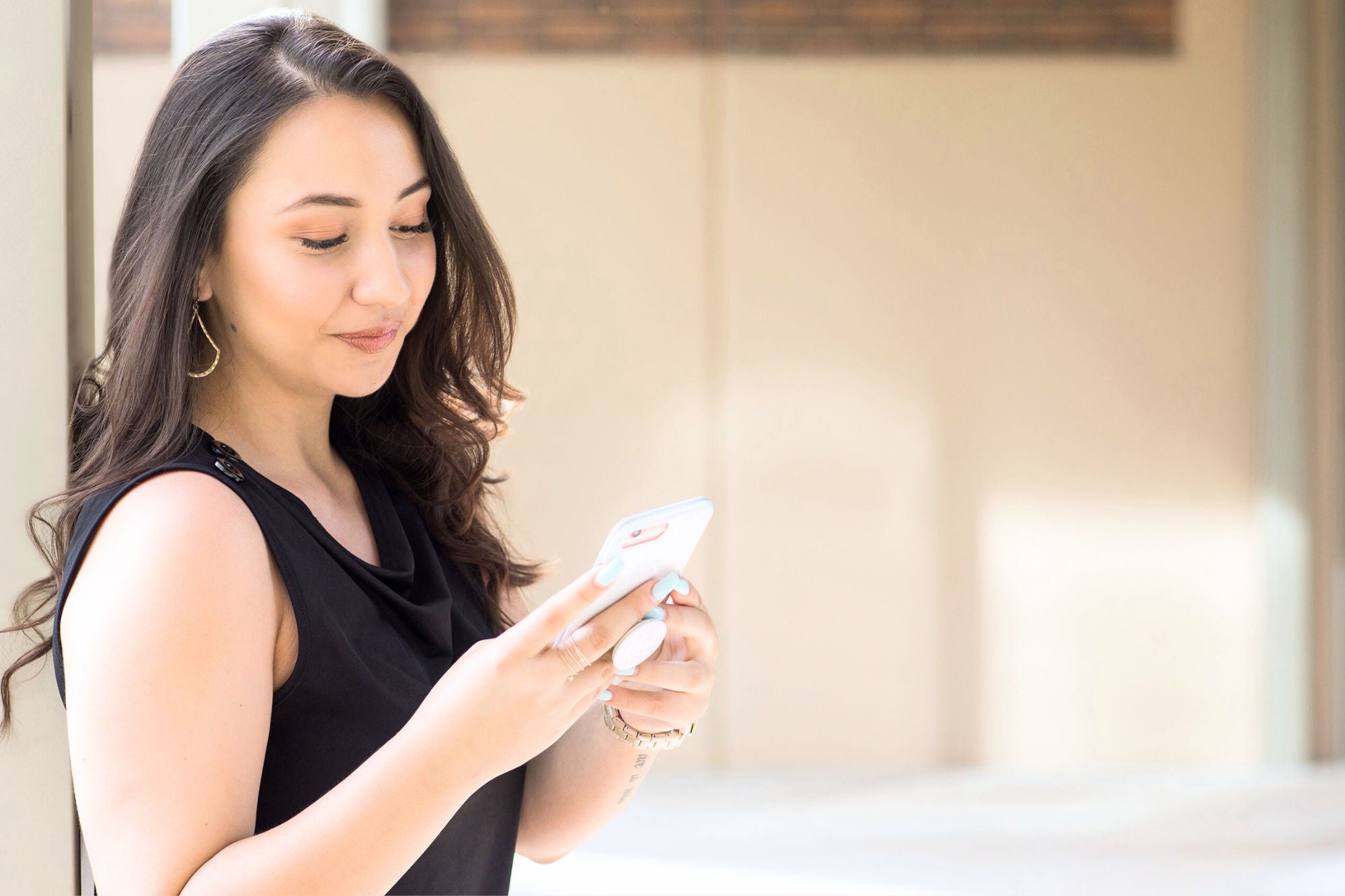 young hispanic woman with lash extensions looking at cell phone