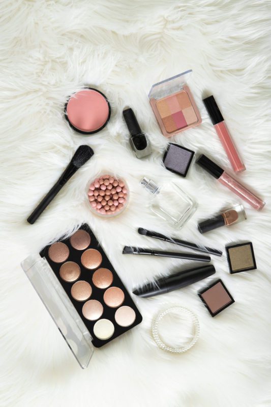 birds eye view of makeup items on white shag rug