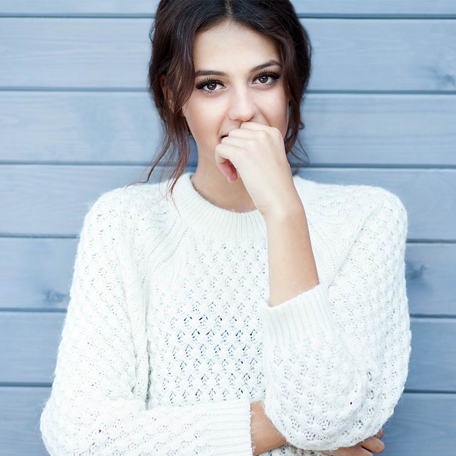 brunette with lash extensions posing in a cable knit sweater
