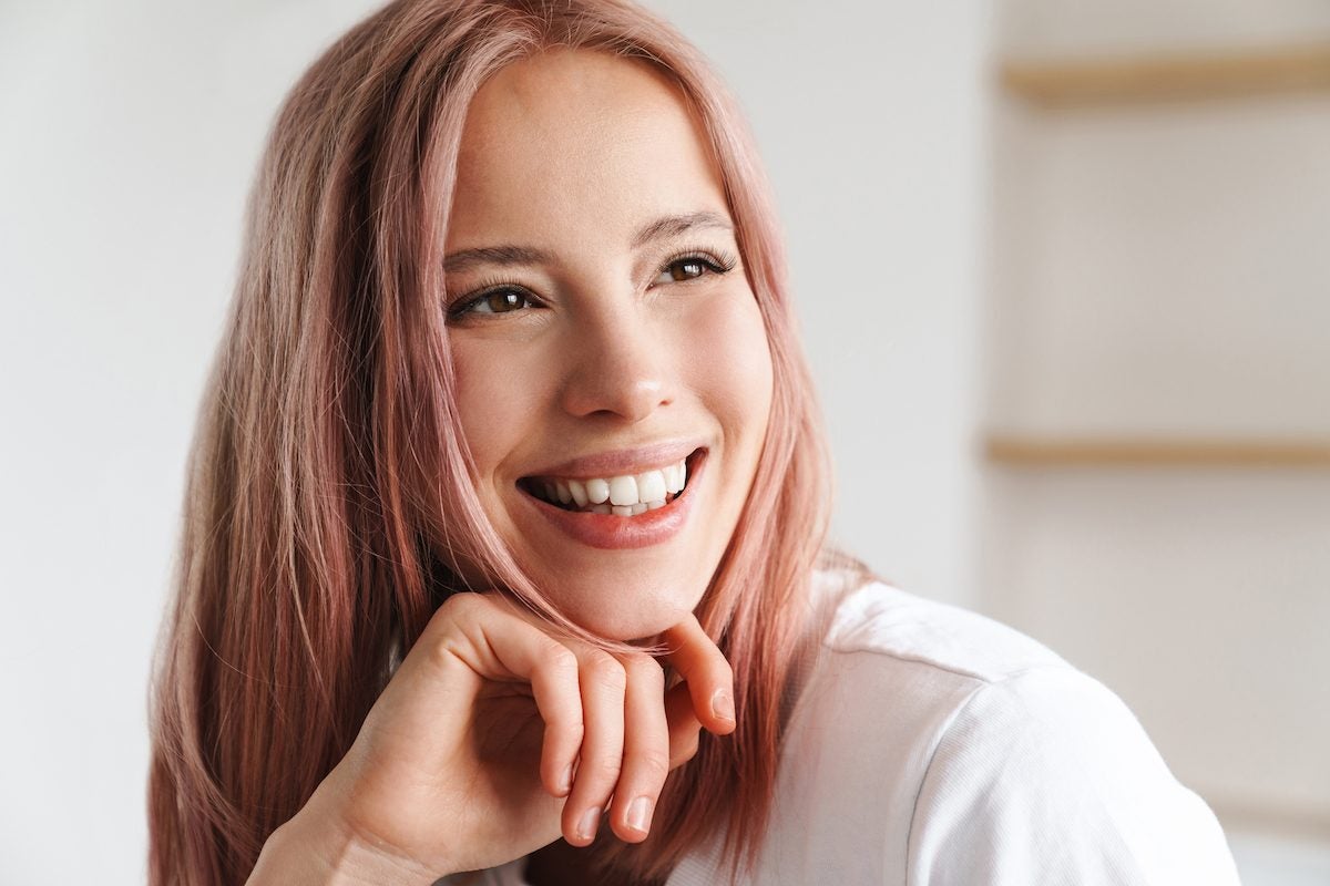 young asian woman with pink hair smiling big with new lash extensions for the new year
