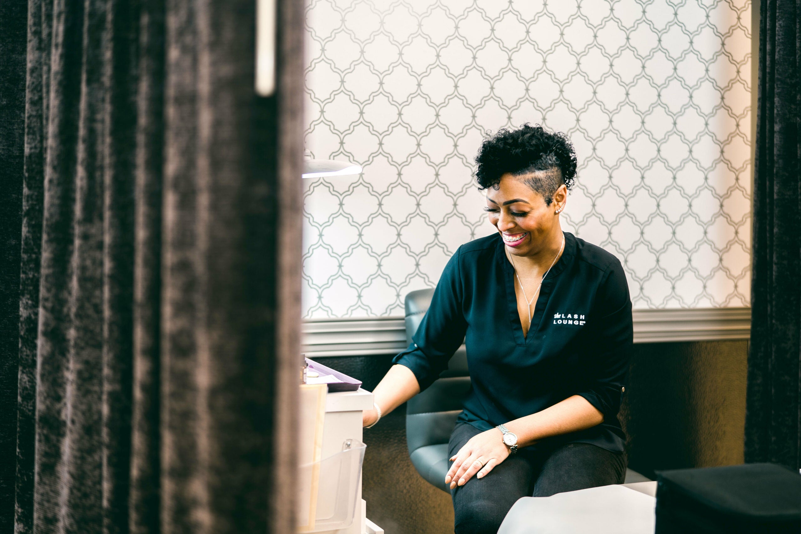 A smiling lash tech sitting and prepping before a lash appointment