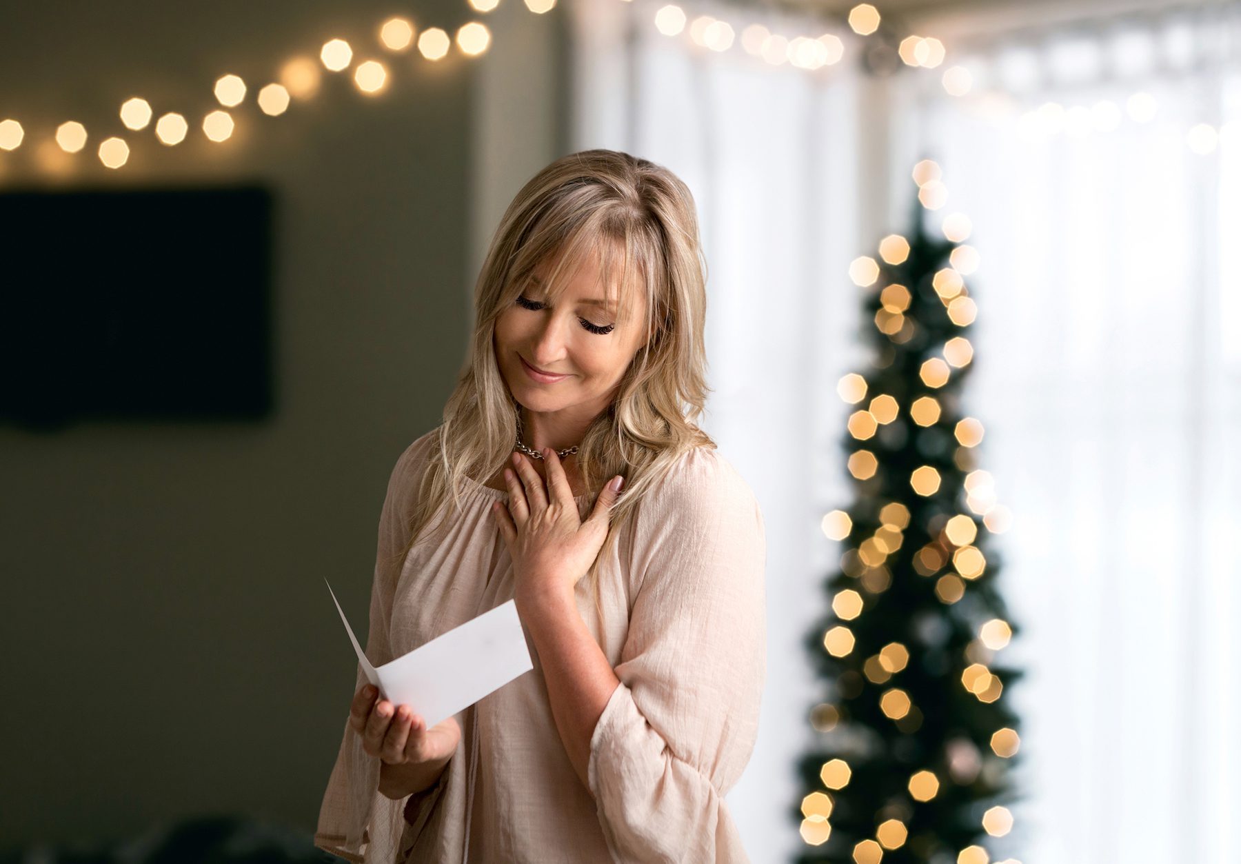 blonde woman with lashes reading heartfelt holiday card and gift