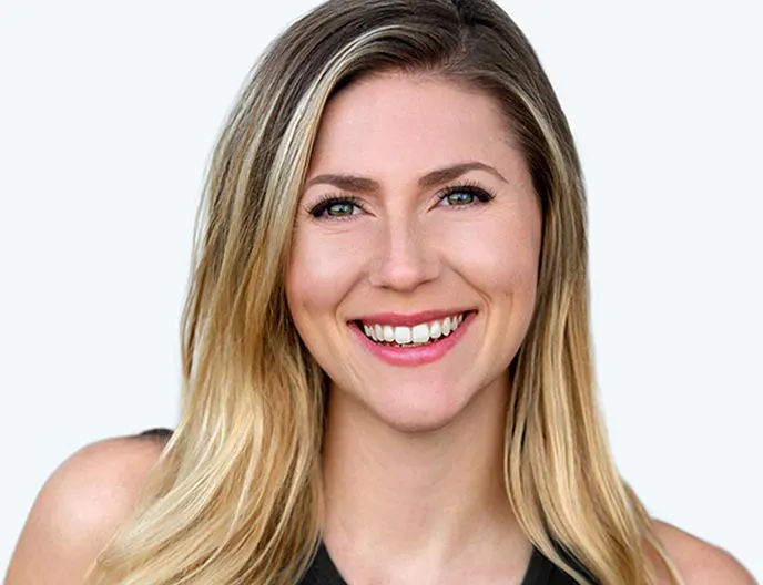 Middle-aged woman with eyelash extensions smiling while wearing a tank top.