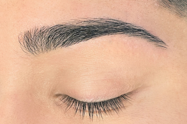 An extreme closeup of a Hispanic man’s eyebrow after receiving a brow threading service from The Lash Lounge.