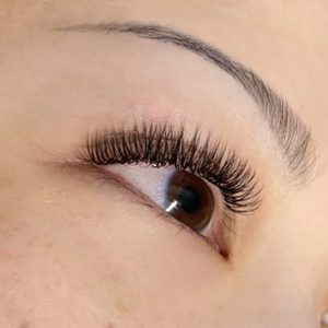 A close-up of a woman's eye and eyelash extensions