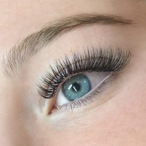 A close-up of a woman's eye and eyelash extensions