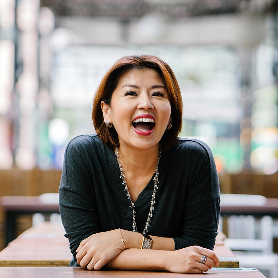 woman with an eyelash lift smiling in a cafe.