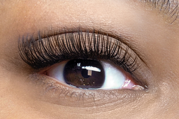 An extreme closeup of a Black woman’s brown eye with “Classic: Level 1” c-curled lash extensions applied from The Lash Lounge.