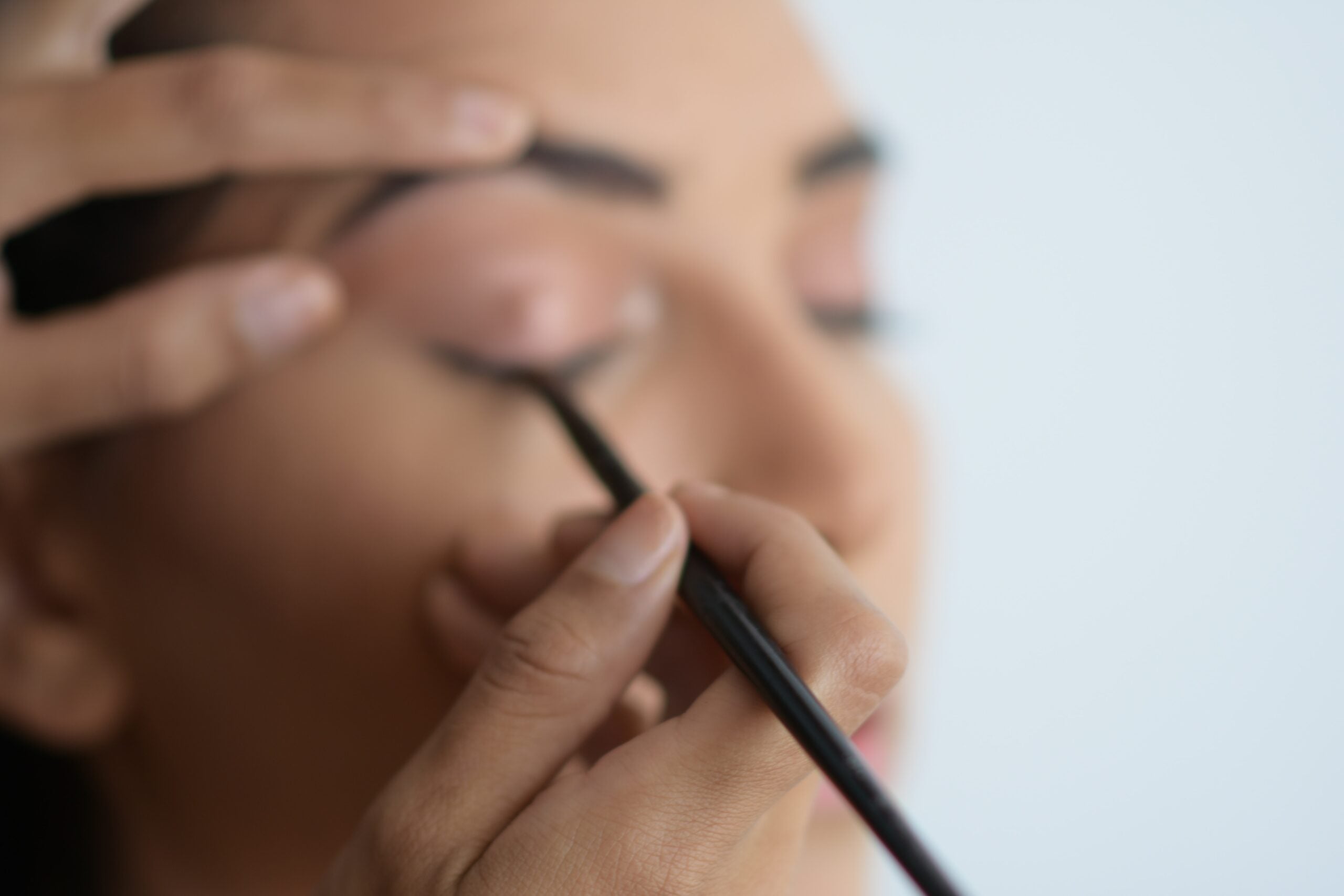 soft focus close-up of woman applying eyeliner