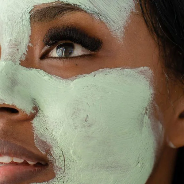 close-up of African American woman with lash extensions and green facial mask