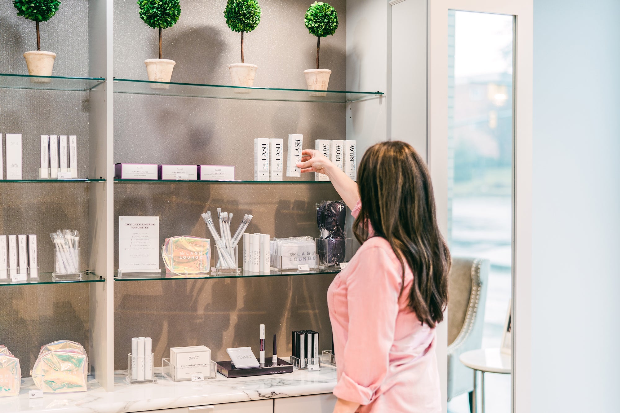 Brunette woman standing in front of retail wall at The Lash Lounge