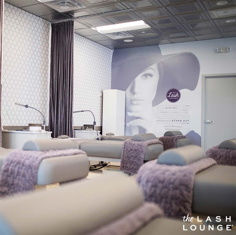 The Lash Lounge luxurious salon service area with spa beds, purple blankets, and company manifesto with empowering words for women