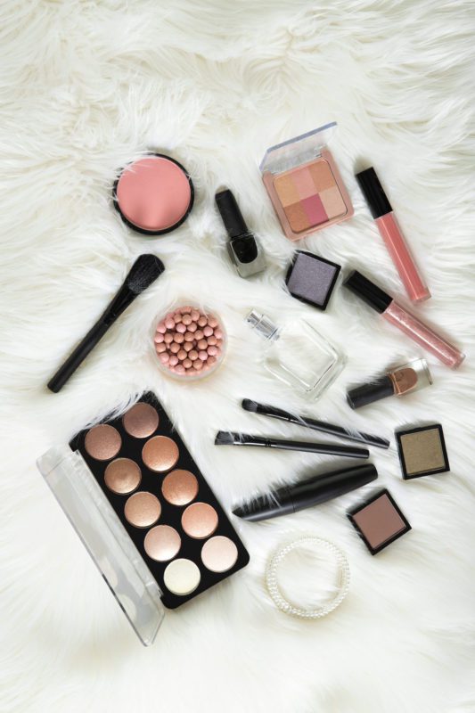 birds eye view of makeup items on white shag rug