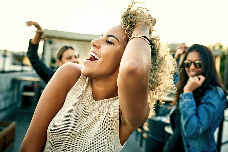 woman with tinting eyebrows and lashes dancing with friends