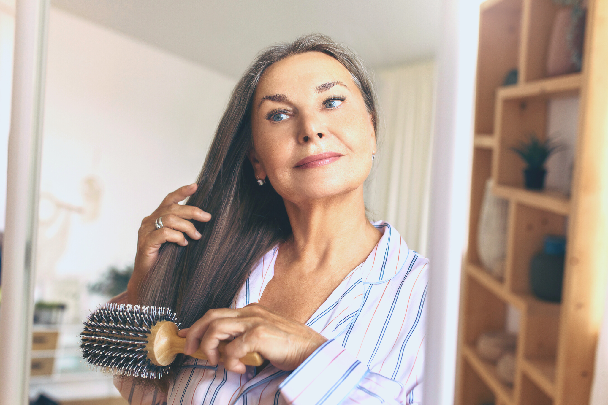 a mature woman with lash extensions brushes her hair