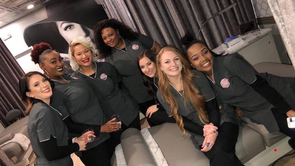 A group of lash stylists in uniform smiling at The Lash Lounge