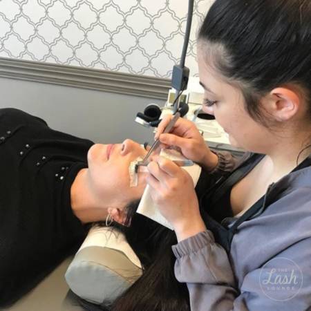 A lash stylist giving a lash extension to a young woman at The Lash Lounge