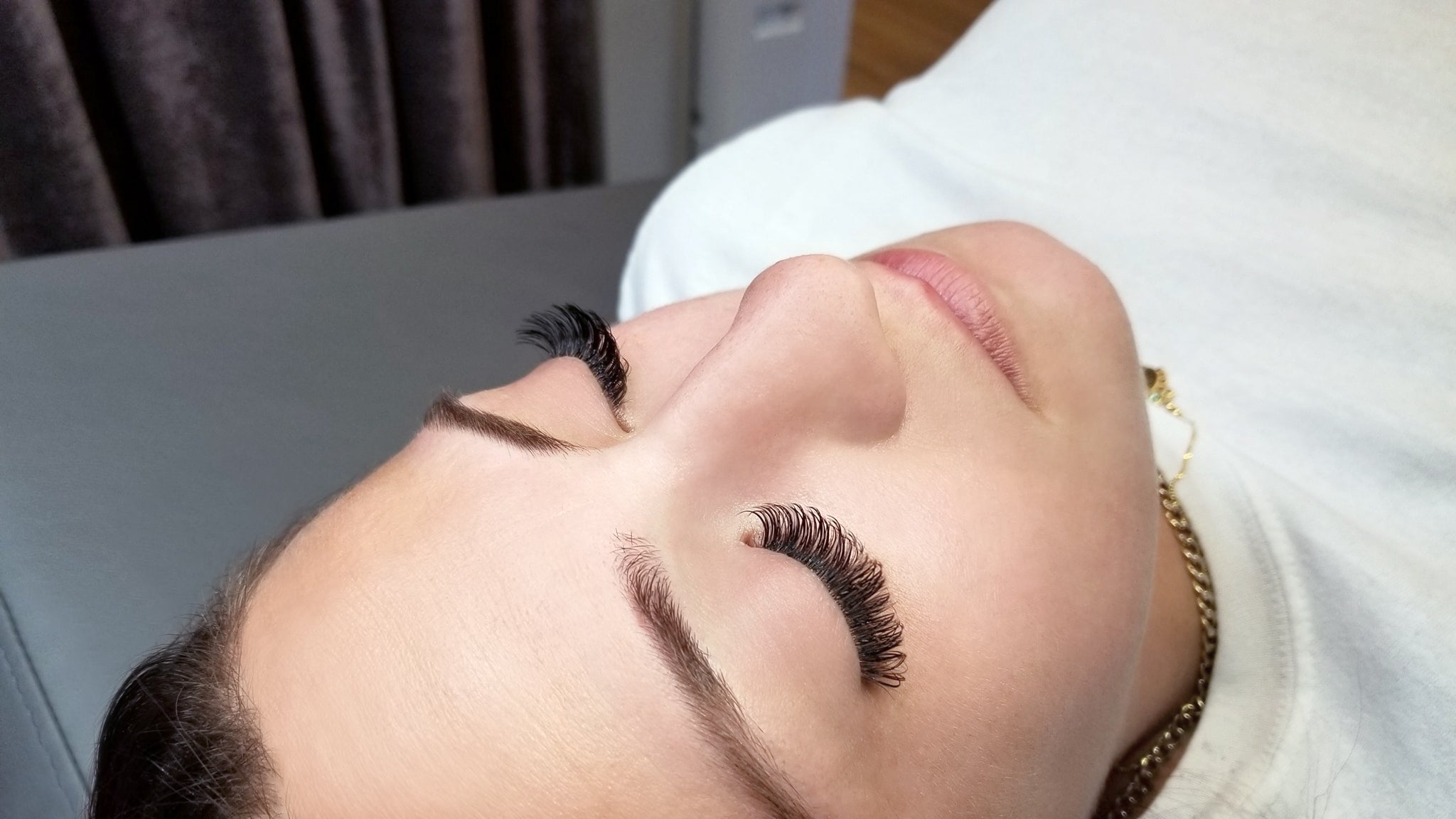 woman with eyes closed after receiving a full set of volume lash extensions