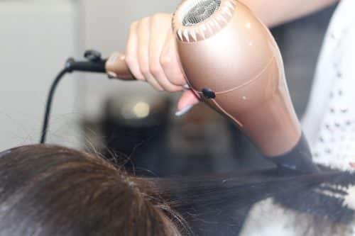 a close up of a hairdresser blow drying a client's hair