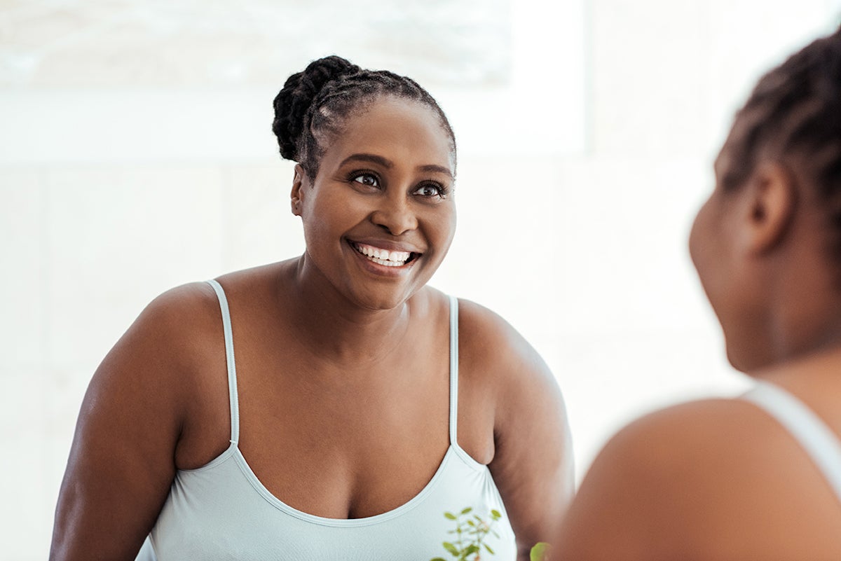 mid shot of plus-sized black woman smiling in mirror