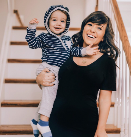 Maria, university program coordinator, mom and blogger, sports lovely lashes from The Lash Lounge on her staircase while holding her toddler son