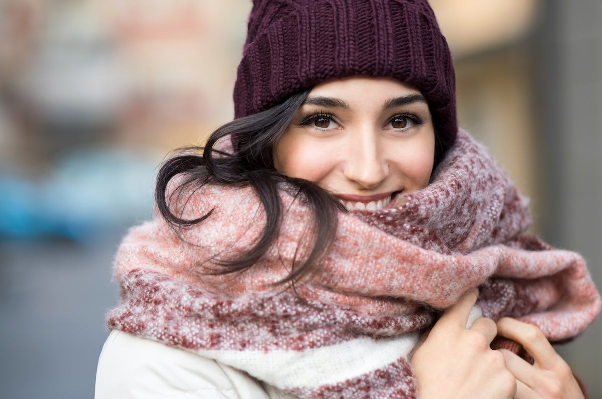 smiling dark haired woman wearing lovely lashes from The Lash Lounge and a winter hat and scarf