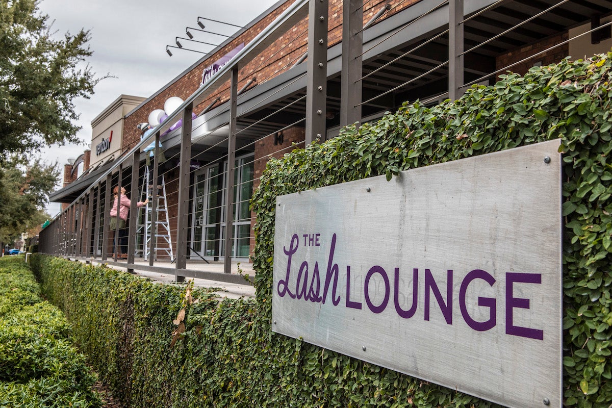 The Lash Lounge sign on leafy wall outside the studio