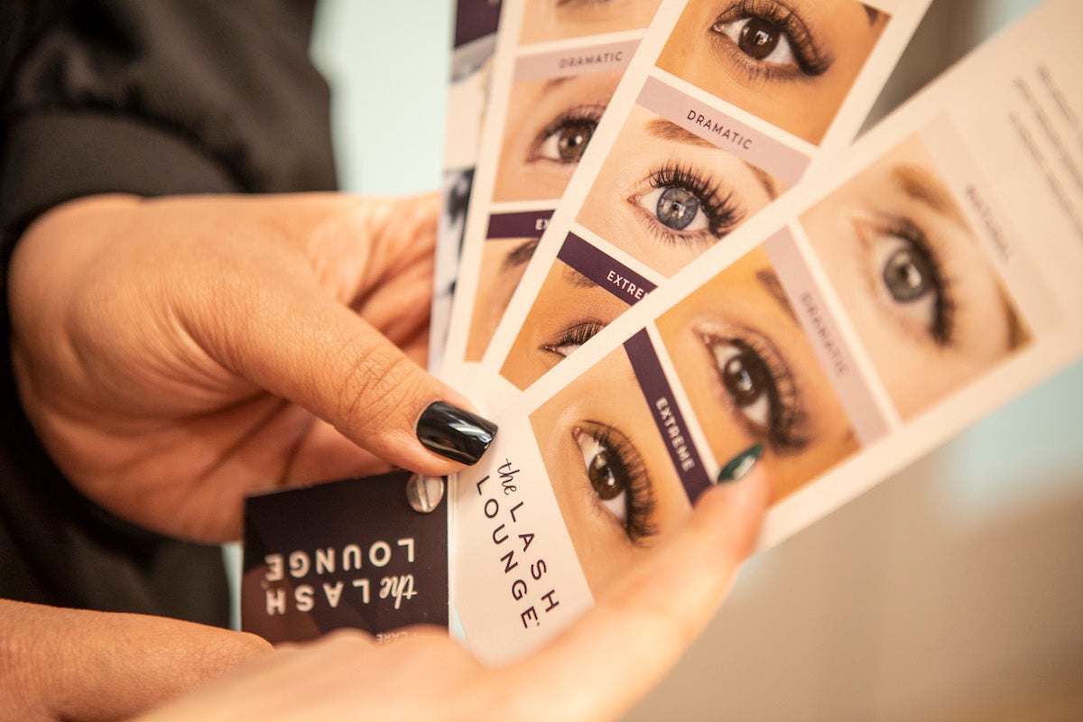 closeup of hands holding the Lash Catalog, the ultimate guide to lash customization