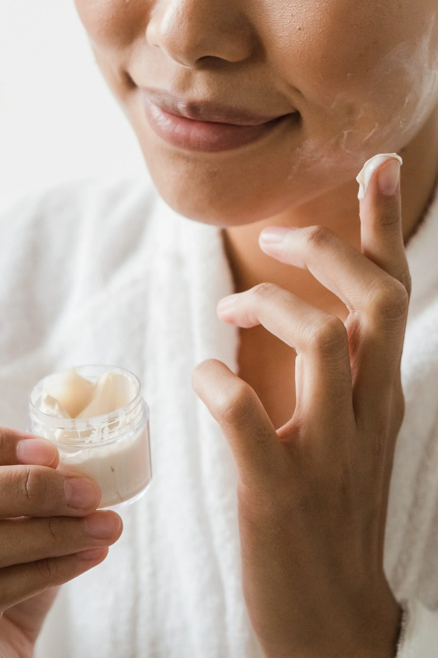 close-up of part of woman's face as she applies moisturizer