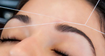 A stylist threading eyebrows on a guest at The Lash Lounge