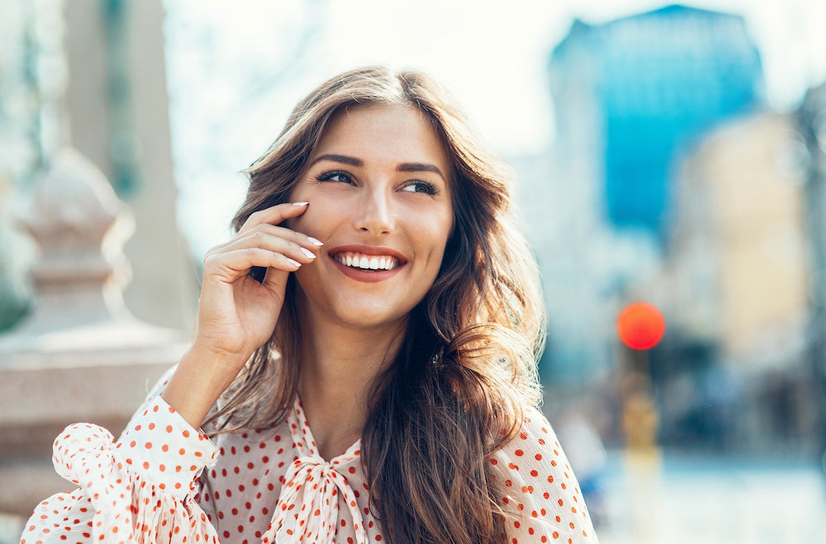 smiling young brunette woman wearing polka dots in the city