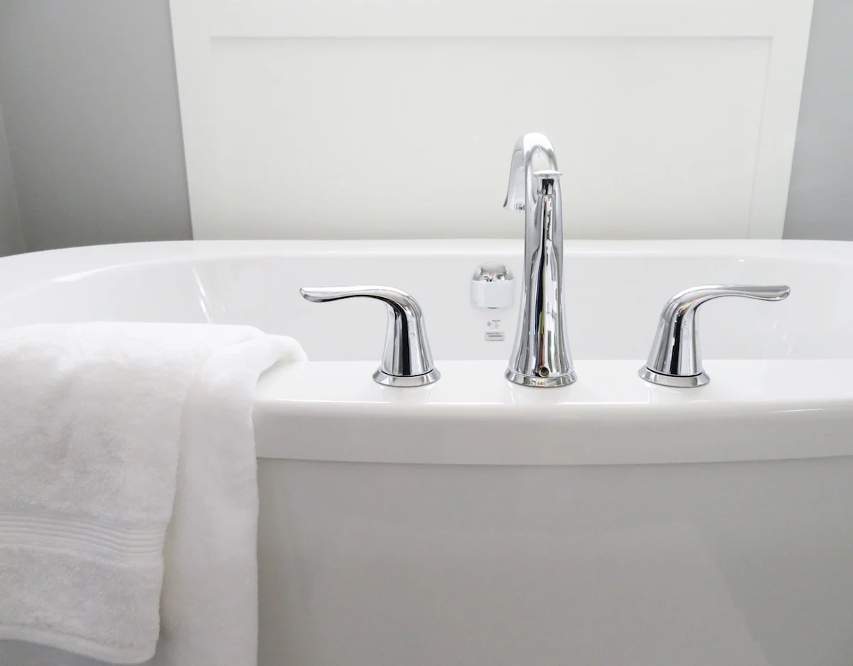 White bathtub with a white towel strewn over the top