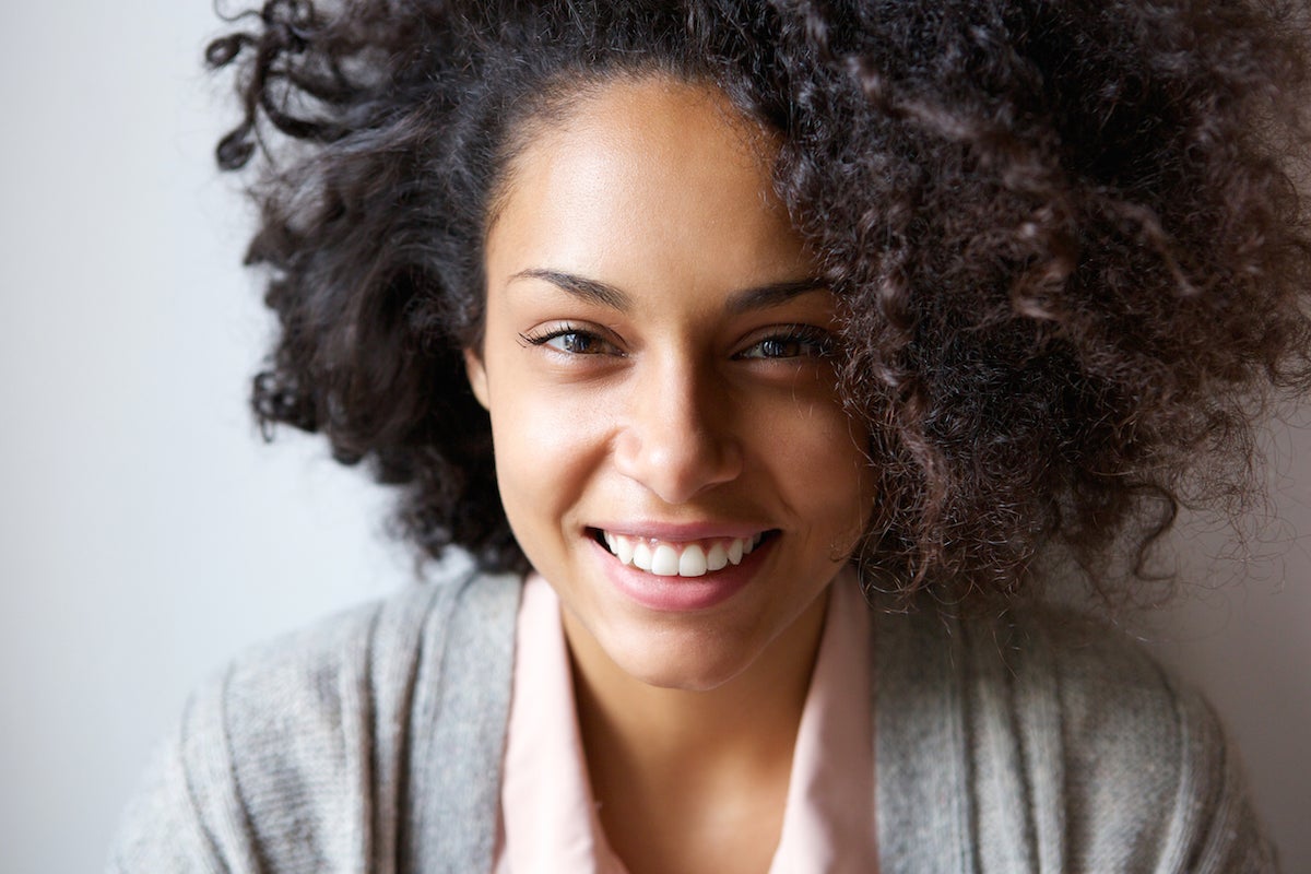Smiling curly haired woman in a sweater with natural lashes