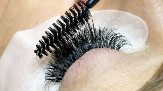 close-up of a lash wand brushing lash extensions