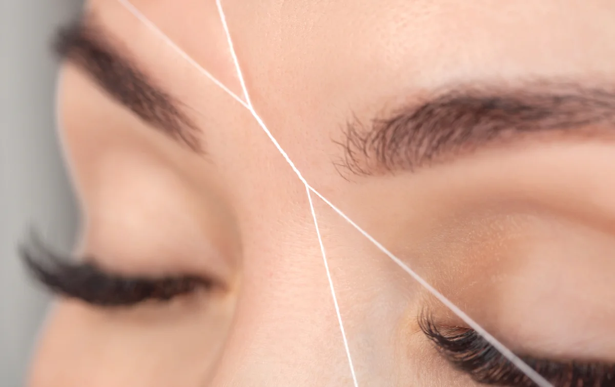 closeup of woman with lash extensions getting brows threaded at The Lash Lounge