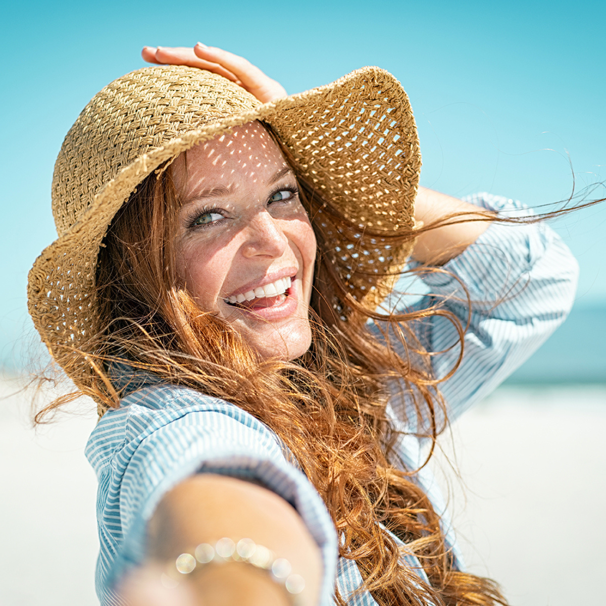 Woman on beach thinking about swimming with eyelash extensions