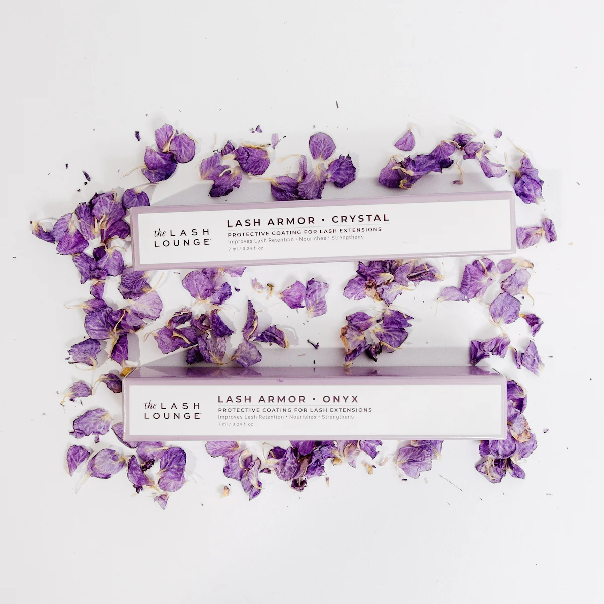 Lash Armor lash sealant boxes from The Lash Lounge atop purple flower petals