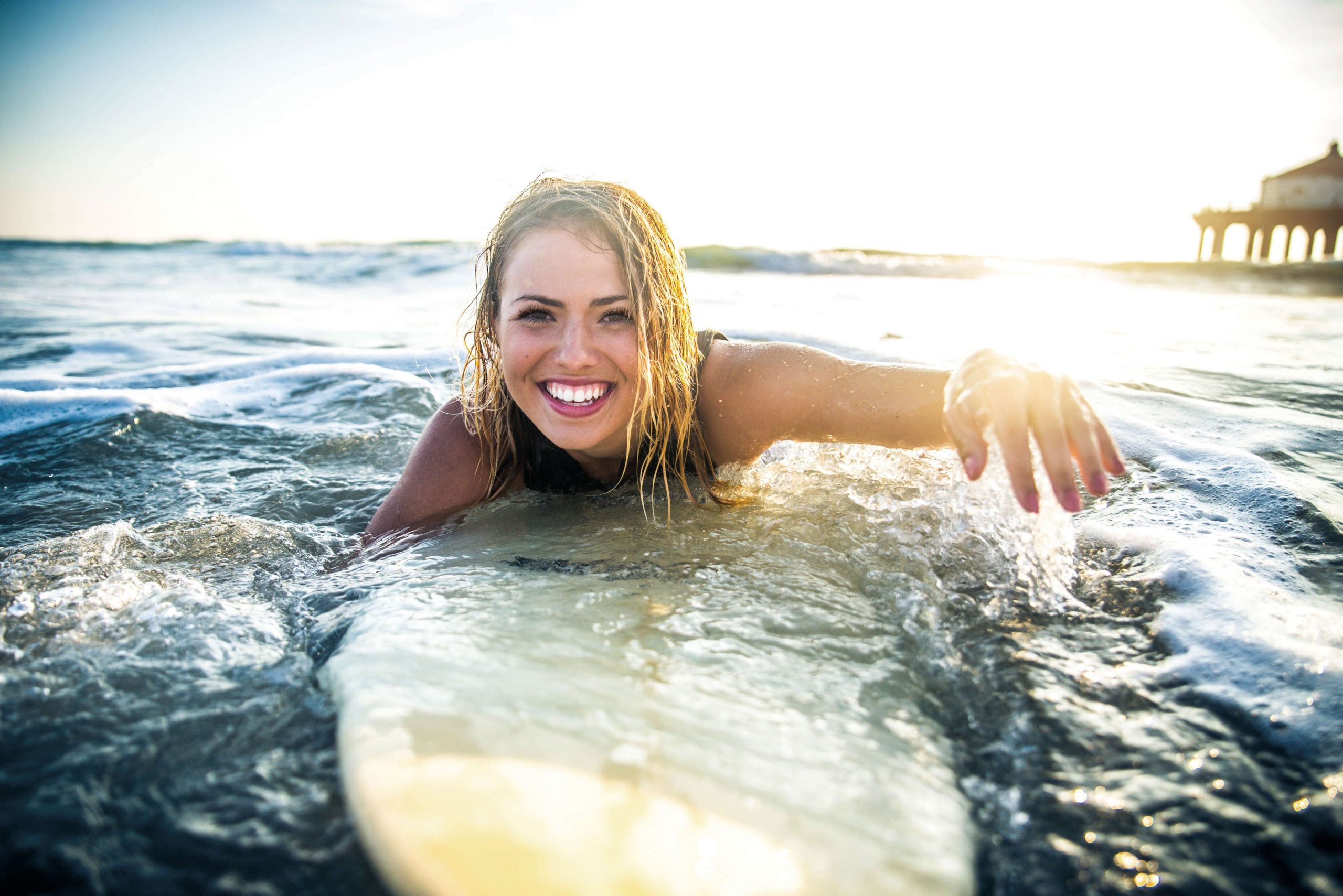 Woman in ocean surfing and swimming with eyelash extensions