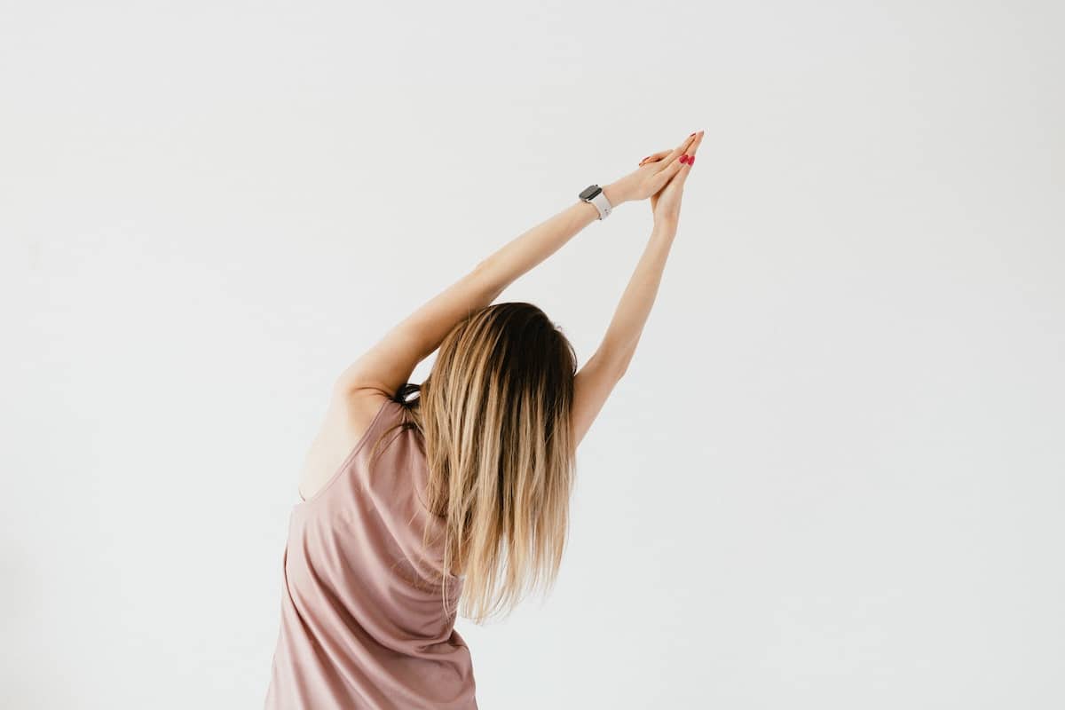 a woman with back turned to camera arms in the air stretching to the right