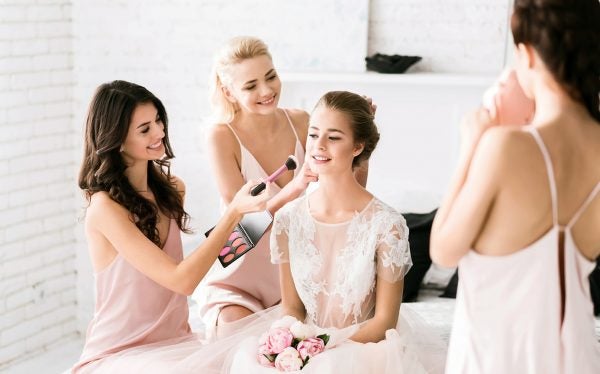 bride with lash extensions getting makeup done by her bridesmaids
