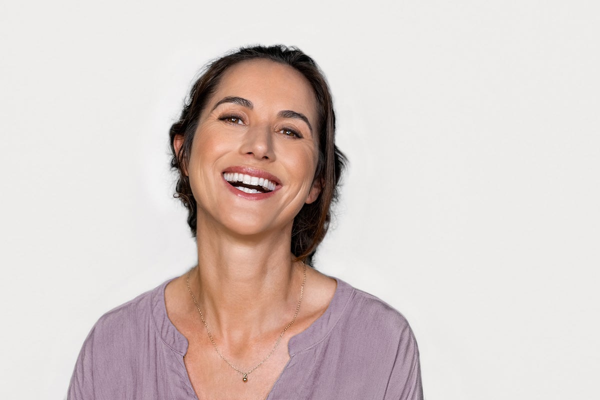 brunette hispanic woman smiling with eyelash extensions