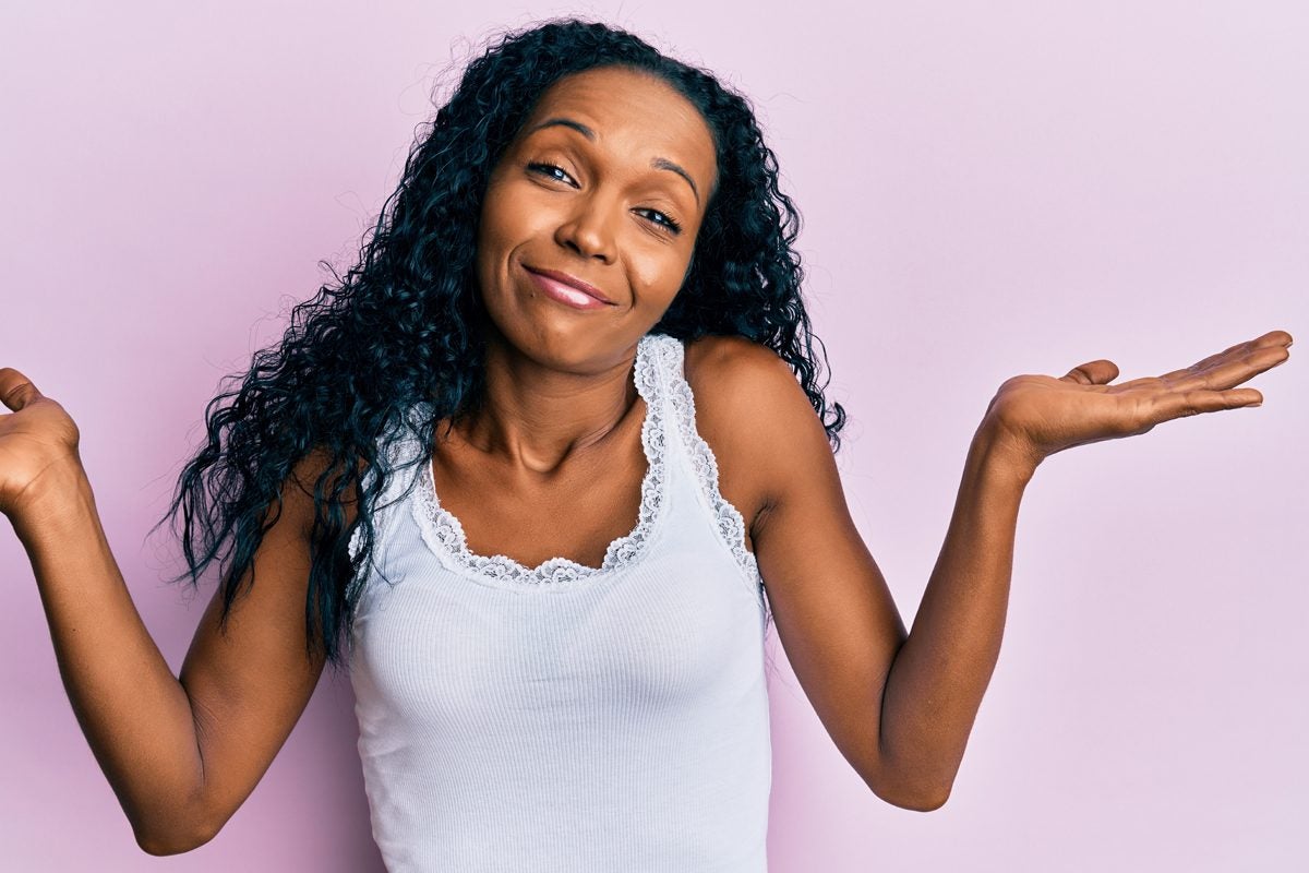 Black girl shrugging shoulders with light purple background