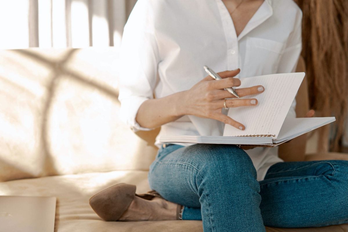mid-shot of woman sitting on sofa looking at a journal