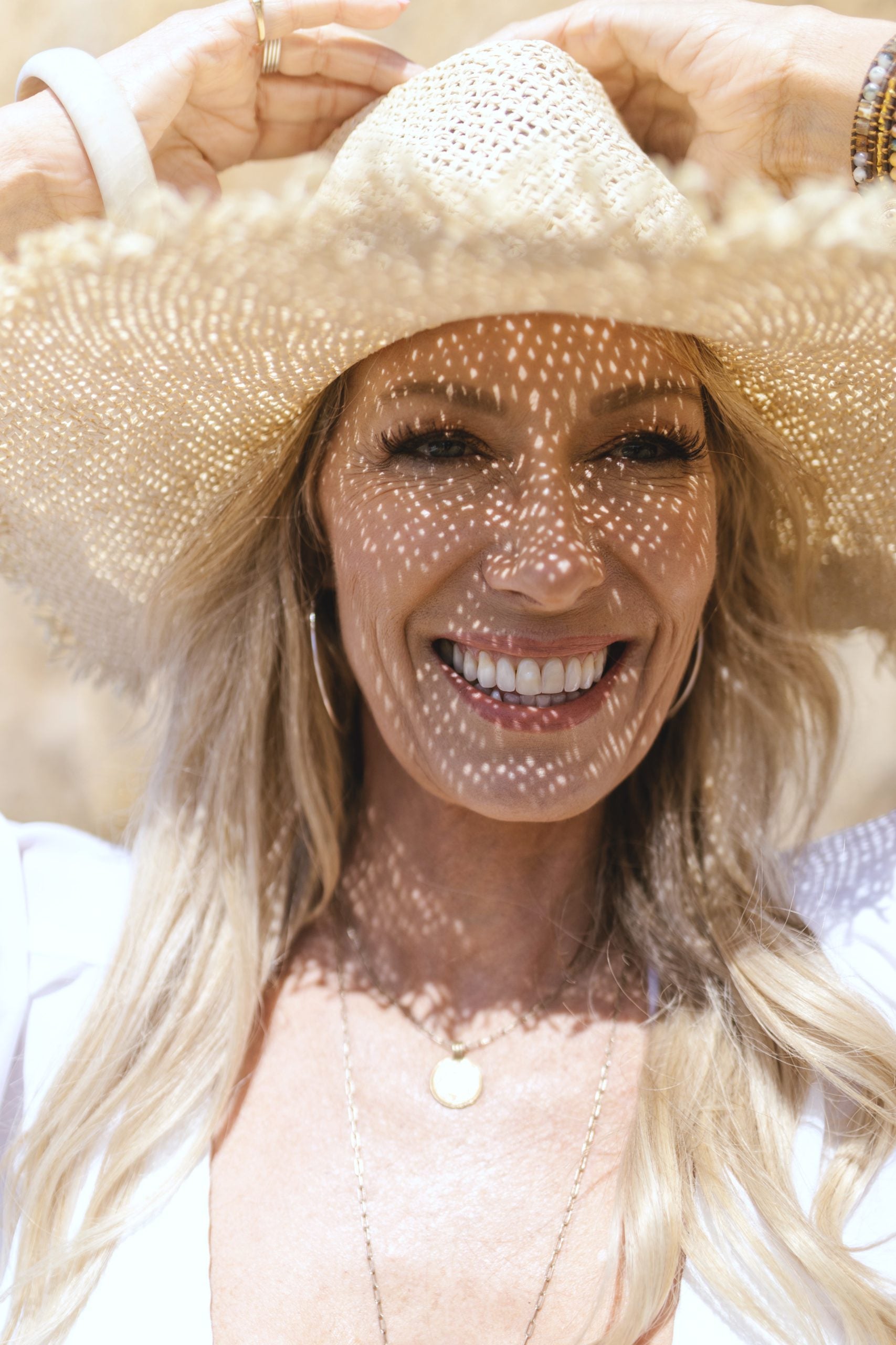 mature blonde woman wearing sun hat with lash extensions
