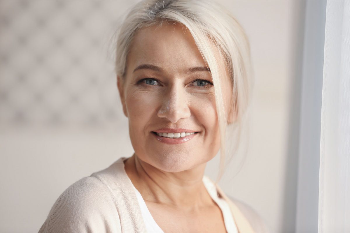 A woman with natural looking brows and makeup faces the camera and smiles