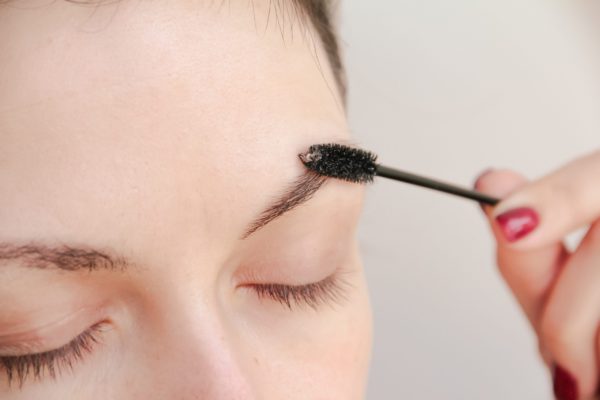close-up of a woman brushing her brows upward