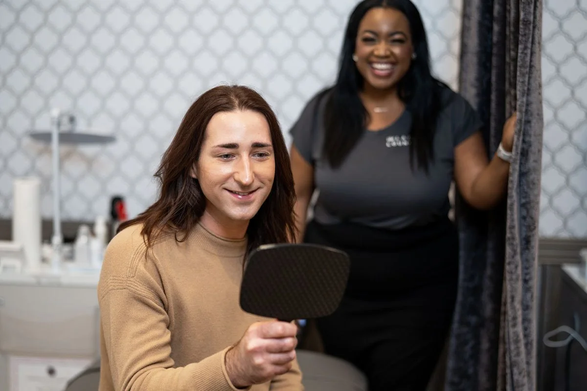 A man holds and mirror and looks at his threaded eyebrows