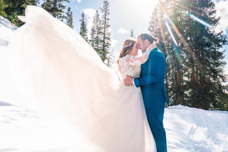 bride and groom standing in snow on their wedding day